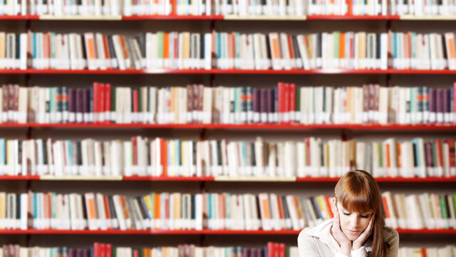 Studerend meisje voor muur met boeken
